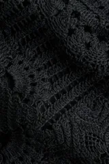 Top negro sin mangas de punto estilo crochet, con cuello redondo, cierre oculto en la espalda y diseño de peplum acampanado con ribetes festoneados.