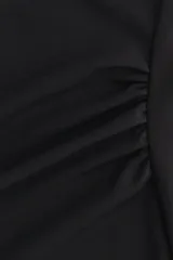 Vestido midi negro confeccionado en punto de crepé, de corte ajustado con escote asimétrico, un bretel fino y un hombro drapeado. Presenta frunces laterales que generan un efecto drapeado en la cintura y largo hasta la rodilla.