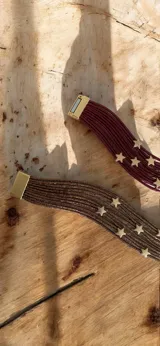 Brazalete de múltiples tiras finas con acabado metalizado, decorado con apliques de estrellas doradas y cierre imantado.