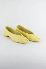 Mocasines de cuero color amarillo, con diseño de costura central en la capellada, taco bajo y punta cuadrada.