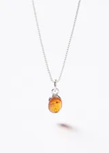 Collar de cadena fina de plata 925 con dije ovalado de piedra ámbar engarzado.