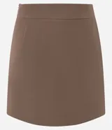 Short pollera de sastrería color rosado, con diseño asimétrico superpuesto en el frente, bolsillos ribeteados decorativos y cierre lateral discreto.