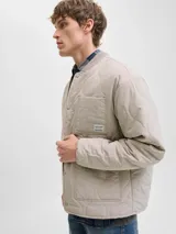 Campera acolchada liviana con diseño matelasse, cuello estilo baseball y cierre frontal con botones a presión. Cuenta con bolsillos frontales tipo parche y un bolsillo pequeño en el pecho con etiqueta de marca. Presenta puños elásticos y un corte recto funcional.