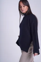 Sweater color crema de media polera, corte holgado y mangas largas. Tejido de punto con detalles acanalados en cuello, puños y ruedo.