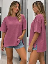 Blusa tipo remera de bambula color rosado, con cuello redondo, mangas cortas amplias, corte oversize y aberturas laterales en el dobladillo asimétrico, más largo en la parte trasera.