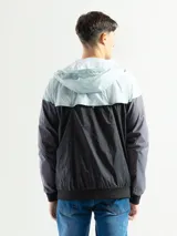 Campera deportiva negra de nylon impermeable con capucha y cierre frontal. Presenta puños y cintura elásticos de tejido acanalado. Tiene un pequeño logo blanco en el pecho.