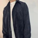 Sobrecamisa de pana negra con cierre frontal de botones, cuello clásico, mangas largas con puños abotonados y un bolsillo en el pecho.
