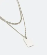 Collar doble dorado con cadena fina y dije rectangular.