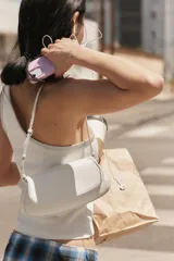 Bolso de hombro color crudo con diseño estructurado, solapa frontal, cierre de botón imantado y asa regulable.