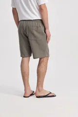 Bermuda de caída suelta con cintura elastizada y cordón regulable, confeccionada en tejido texturado negro.