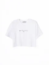 Remera blanca de corte crop, con cuello redondo, mangas cortas y estampa frontal con texto en tipografía cursiva.
