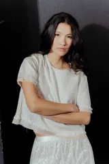 Blusa color crudo de lino con mangas cortas y detalle de flecos en el ruedo y las mangas. Cierre con botón en la espalda.