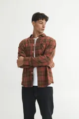 Camisa de franela a cuadros marrones y verdes, corte regular fit, confeccionada en algodón. Tiene cuello solapa clásico, bolsillo en el pecho y botones personalizados.