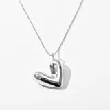 Collar con cadena plateada y dije con forma de corazón inflado.