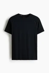 Remera deportiva negra de manga raglán con cuello redondo y costuras planas, diseñada con ajuste Muscle Fit y tejido funcional transpirable.