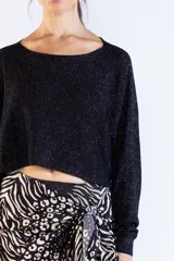 Sweater negro de punto con hilo lurex brillante, escote bote, mangas largas y corte corto tipo crop.
