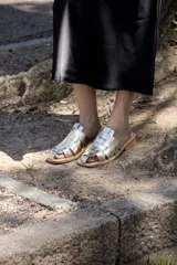 Sandalias bajas doradas con tiras de cuero entrelazadas.