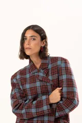 Blazer de corte oversize con estampado de cuadros en tonos azul, bordó y marrón. Presenta solapas clásicas, bolsillos con solapa en el frente y cierre frontal con botones.