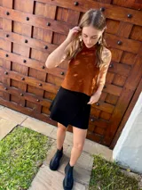 Top halter confeccionado en cuero color camel, con diseño sin mangas, espalda descubierta y ajuste mediante tiras.