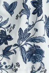 Vestido corto de algodón con estampado floral en tonos azules sobre base blanca, escote en V y mangas globo de longitud al codo. Presenta elástico fruncido en el pecho y la cintura, con falda evasé de vuelo.