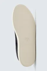 Zapatilla urbana de hombre confeccionada en piel con acabado de serraje, diseño minimalista con cordonera oculta y suela de goma a contraste.