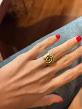 Anillo de diseño artesanal con motivo de espiral en la parte superior, elaborado en bronce con acabado bicolor.