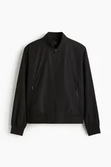 Campera bomber negra, de corte estándar, con cuello elevado acanalado, cierre frontal y bolsillos laterales con cierre. Presenta puños y bajo con ribete acanalado ancho.