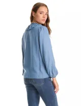 Blusa de lyocell con cuello a la base, escote en V y detalle de volados frontales. Presenta cierre con botones y mangas largas con puños elásticos fruncidos.