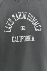 Sudadera de cuello redondo en color rosado, con mangas cortas amplias y estampa frontal con texto en color negro.