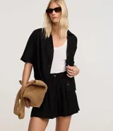 Short runner de viscolino, con cintura elástica, botón decorativo y bolsillos laterales. Presenta un corte evasé holgado con bajo redondeado.