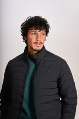 Campera acolchada negra con cierre frontal, cuello alto y diseño de costuras horizontales. Presenta un ajuste entallado y tejido exterior resistente al agua.