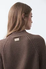 Polera de punto color marrón, con cuello alto y diseño de trenzas verticales en el frente y tejido acanalado en las mangas. Presenta mangas raglán y terminaciones acanaladas en puños y ruedo.