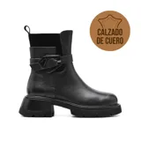 Bota corta de cuero negro con elástico en la parte superior y correa con hebilla decorativa. Tiene suela track y plataforma.