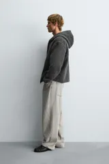 Sobrecamisa de corte relajado confeccionada en tejido con textura efecto pelo. Presenta cuello con capucha, manga larga, bolsillos laterales y cierre frontal con cremallera.