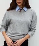 Buzo de algodón gris con cuello redondo, mangas largas con puños ajustados y aplicación de mini beads brillantes distribuidas por toda la prenda.