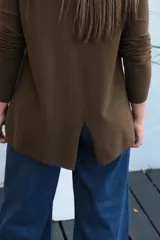 Sweater de punto color chocolate, con cuello redondo, manga larga y puños acanalados. Presenta un corte holgado con ruedo asimétrico.