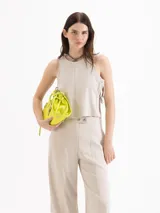 Top de twill color beige, de silueta recta y diseño sin mangas con cuello redondo. Se destaca por sus aberturas laterales con lazos regulables y remaches metálicos.