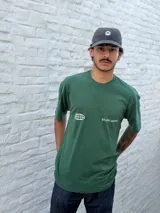 Remera oversize color verde bosque con estampado minimalista en blanco en el pecho: un globo terráqueo estilizado y el texto "STUDIO ARCHIVE".