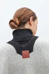 Capa abierta tejida en jacquard color gris y negro con diseño geométrico y detalle de pompones en el borde inferior.