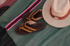 Chinelas tipo ojota con tiras de cuero en color amarillo y marrón, con base de madera y suela de goma.