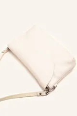 Cartera bandolera color beige, confeccionada en 100% cuero, con solapa redondeada, detalle de flor grabada y correa larga ajustable.
