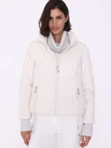 Campera puffer color crema con relleno de poliéster, cierre frontal y bolsillos laterales con cierre.