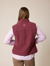 Chaleco de sherpa color beige con cierre frontal completo, cuello alto y bolsillo con cierre en el pecho que incluye un detalle circular con logo.