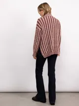 Sweater de punto con diseño de trenzas verticales, cuello alto y silueta oversize. Presenta un patrón bicolor en tonos azul y azul oscuro, con mangas largas y terminaciones en tejido acanalado.