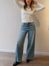 Pantalón de jean con corte wide leg y tiro medio-alto. Presenta un lavado gris azulado desgastado con acabado vintage y ruedo desflecado.