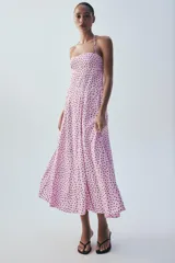 Vestido midi de color rosado con estampado de lunares negros, cuello halter con tirantes finos ajustables, escote recto y diseño fluido con volumen.