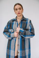 Tapado largo estilo camisa confeccionado en paño italiano, con diseño a cuadros en tonos de azul, gris y negro. Cuenta con cuello clásico, cierre frontal con botones, bolsillos con solapa en el pecho y mangas largas.