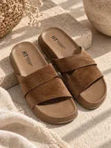Sandalias planas con base marrón y tiras cruzadas en color beige de textura suave.