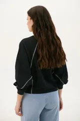 Buzo negro de corte cropped con mangas largas abullonadas y costuras a la vista en color blanco.