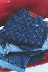 Pantalón de jean azul denim con tiro bajo, corte oversize y grabado láser con monograma.